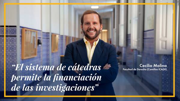 Un hombre sonriente de pie en un pasillo de una facultad, compartiendo una frase sobre la financiación de investigaciones.