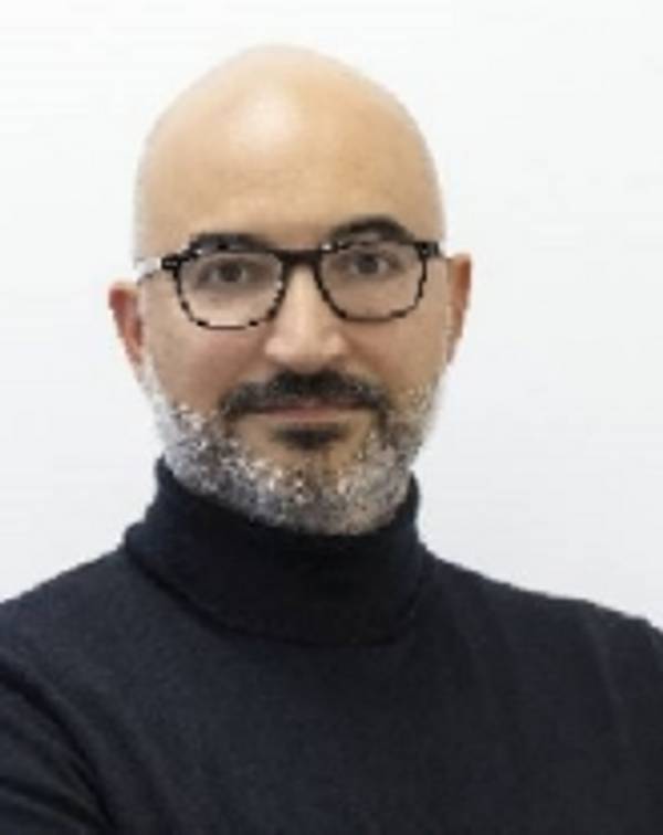 Portrait of a bald man with a beard, wearing glasses and a black turtleneck.