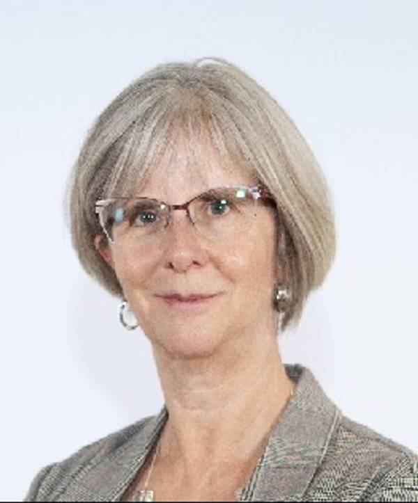 Retrato de una mujer con cabello corto y canoso, usando gafas y una blazer.