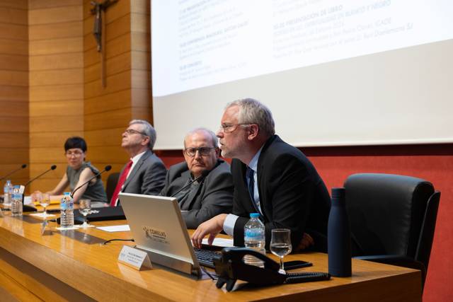 Una mesa de conferencias con varios ponentes discutiendo en un entorno académico.