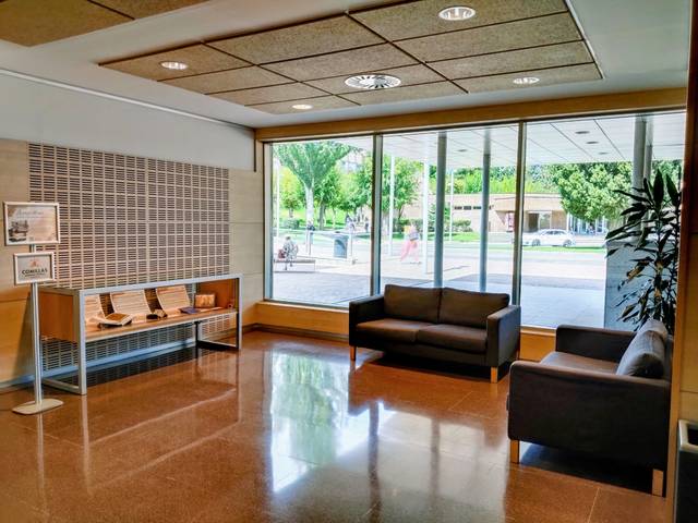 Una sala de espera moderna con sofás y grandes ventanas que ofrecen una vista al exterior.