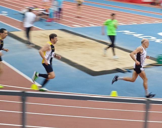 Un grupo de corredores compite en una pista de atletismo cubierta.