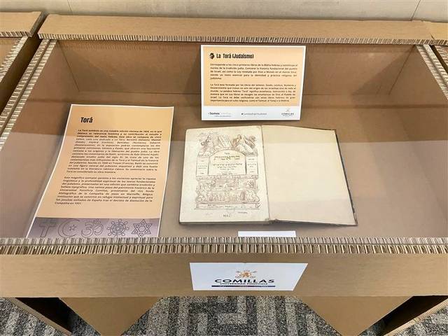 Una vitrina que presenta un libro antiguo junto a un panel informativo en un entorno de exposición.