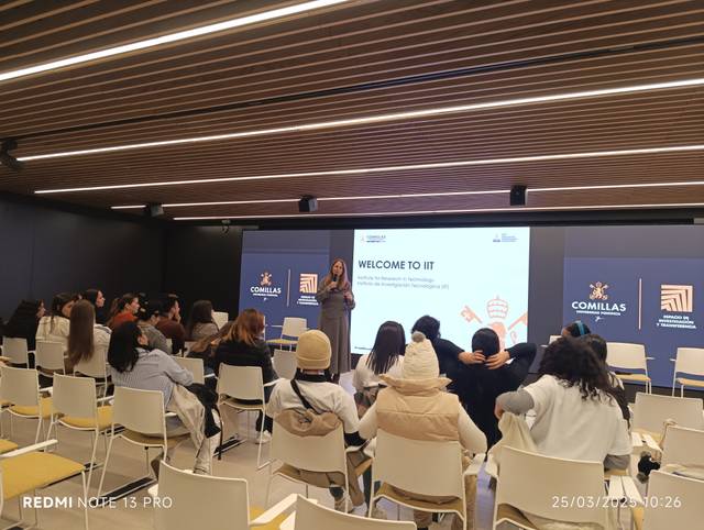 Una ponente está dando la bienvenida en un evento en un salón con auditorio.