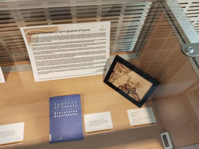 La imagen muestra un vitrina con documentos y libros sobre los Ejercicios Espirituales de San Ignacio de Loyola.