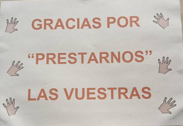 Cartel con el texto 'GRACIAS POR "PRESTARNOS" LAS VUESTRAS' acompañado de ilustraciones de manos.