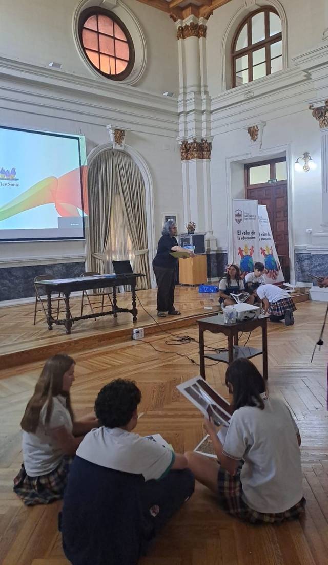 Un grupo de estudiantes asiste a una presentación en un aula amplia y luminosa.