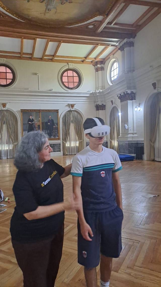 Una mujer explica a un niño que usa un visor de realidad virtual en una habitación iluminada.