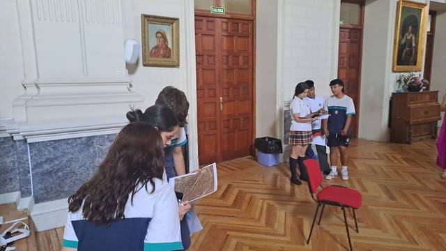 Un grupo de niños conversando y revisando un documento en un salón amplio.