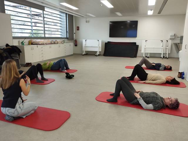 Un grupo de personas realizando ejercicio en una sala, sobre alfombrillas rojas.