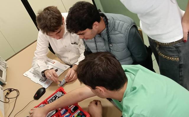 Tres personas trabajan juntas en un proyecto técnico, observando y manipulando componentes electrónicos en una mesa.