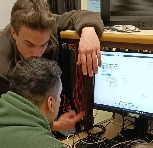 Dos personas interactuando mientras observan una pantalla de computadora.