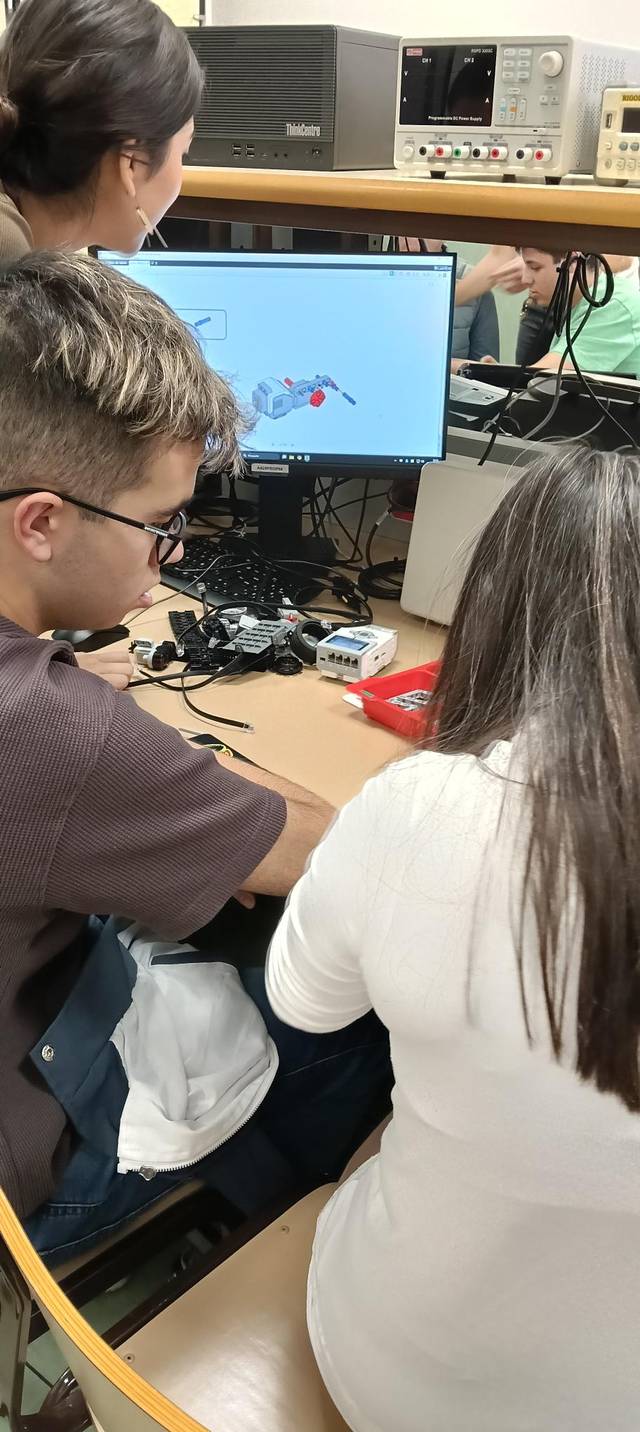 Estudiantes trabajando en un proyecto frente a una computadora en un laboratorio.