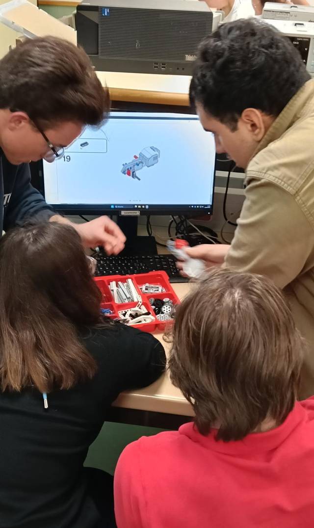 Un grupo de personas trabajando en un proyecto de robótica frente a una computadora.