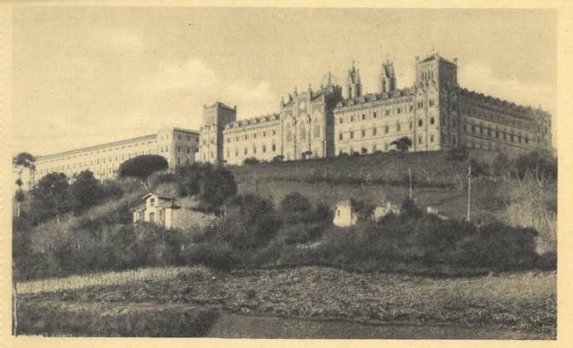 Vista antigua en blanco y negro del Palacio de Escorial en un paisaje campestre.