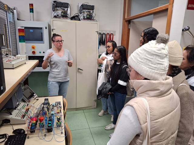 Un grupo de estudiantes escucha atentamente a una instructora que les explica sobre tecnología en un laboratorio.