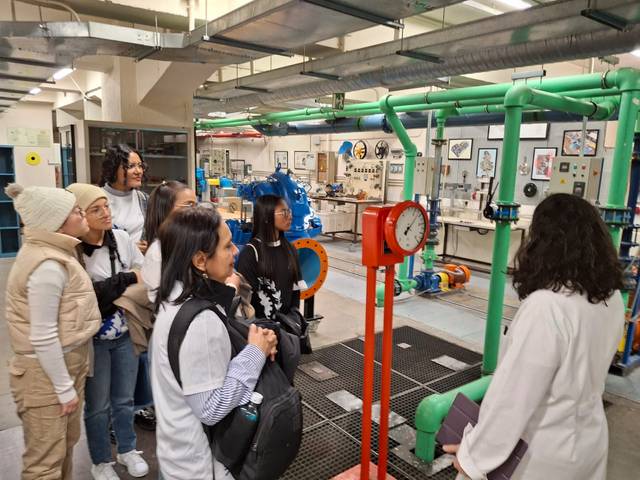 Un grupo de estudiantes observa un sistema de tuberías en un laboratorio de ingeniería.