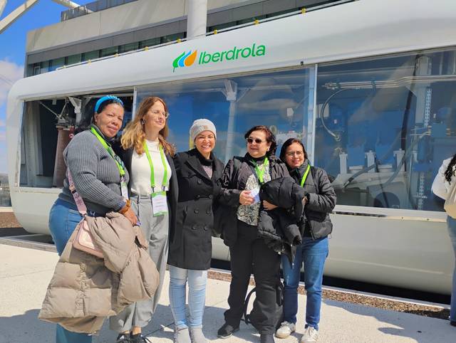 Un grupo de seis personas sonriendo frente a un vehículo de Iberdrola.