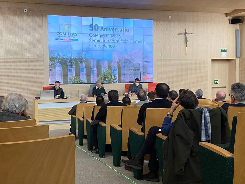 Un evento celebrado en el Seminario Pontificio Comillas, con una audiencia atenta mientras dos ponentes discuten frente a ellos.